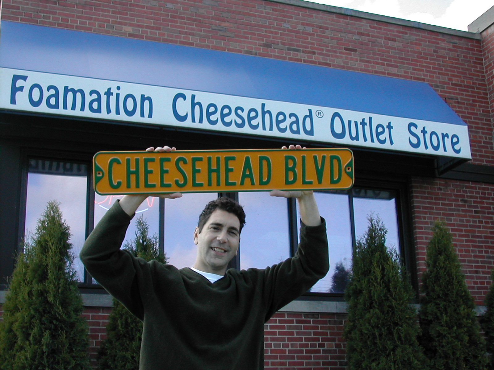 Ralph Bruno, the Cheesehead creator, stands outside the Foamation Inc. Cheesehead Outlet Store. Foamation sells a variety of spin-offs, including the Cheesehead Ave. road sign. Photo by Michelle Wexler